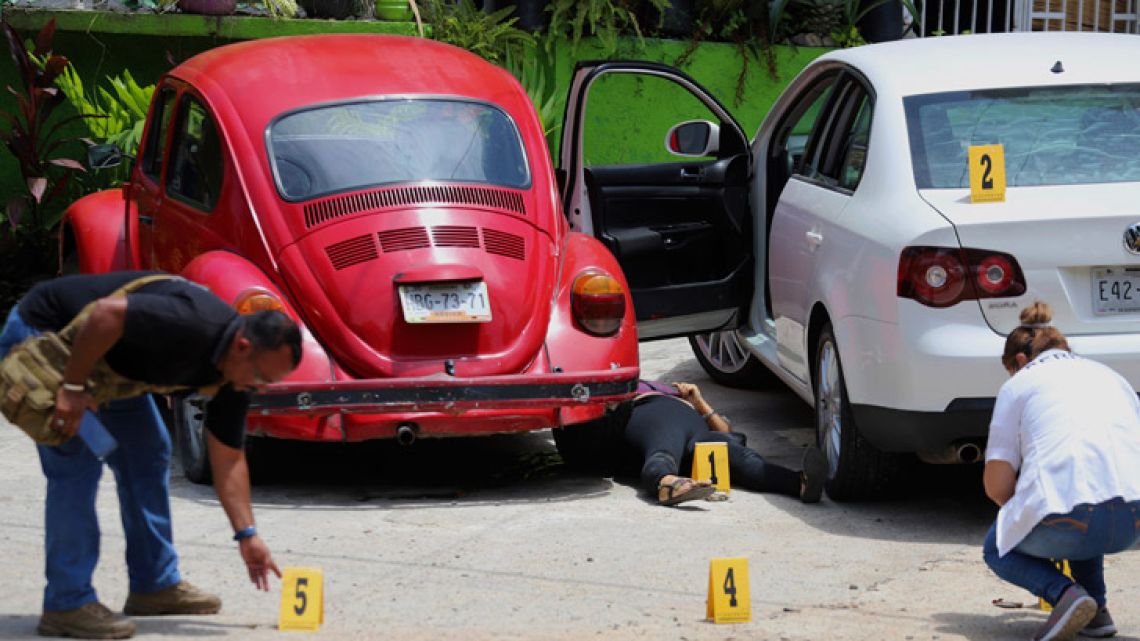 Forensics place numbers by evidence near the body of a woman who was found dead between two cars parked outside a restaurant in Acapulco, Mexico. Homicides in Mexico rose by 16 percent in the first half of 2018, as the country again broke its own records for violence.