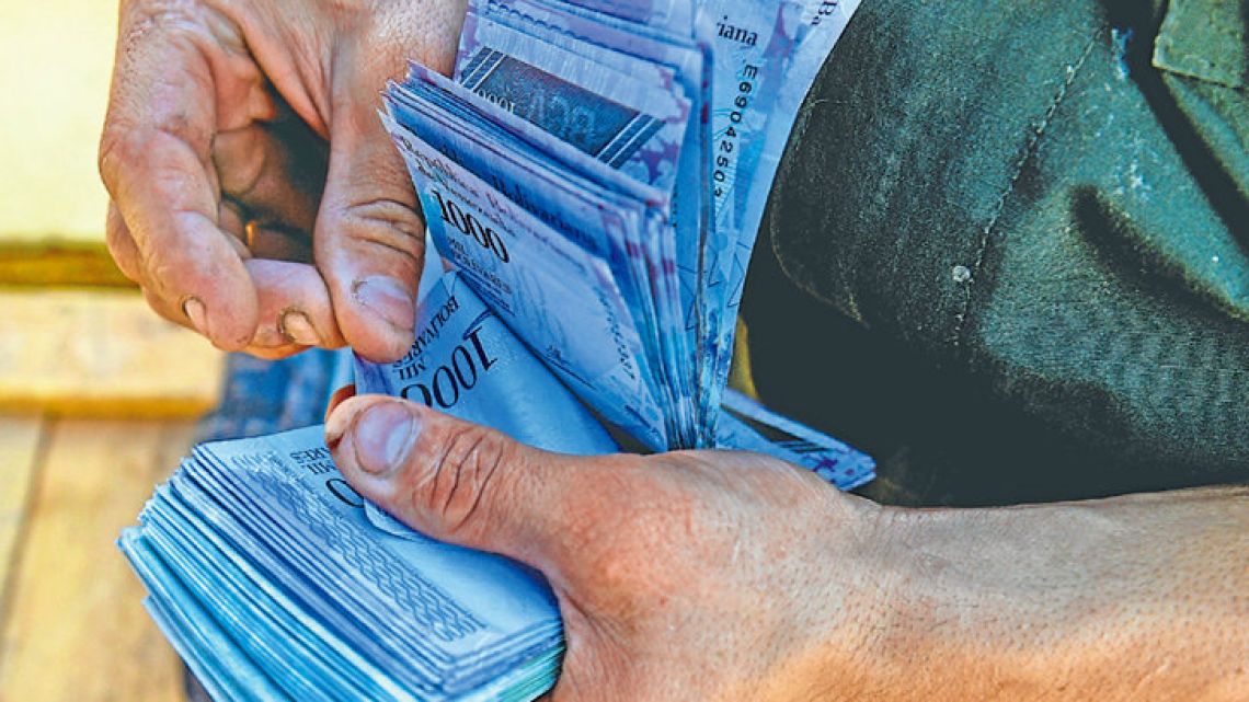 A man counts 1,000-bolívar-bills to buy groceries at the municipal market of Coche, a neighbourhood of Caracas.