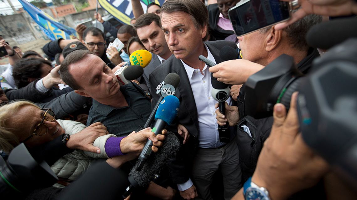 National Social Liberal Party presidential candidate Jair Bolsonaro talks to the press as arrives to campaign at the Madureira market in Rio de Janeiro, Brazil.