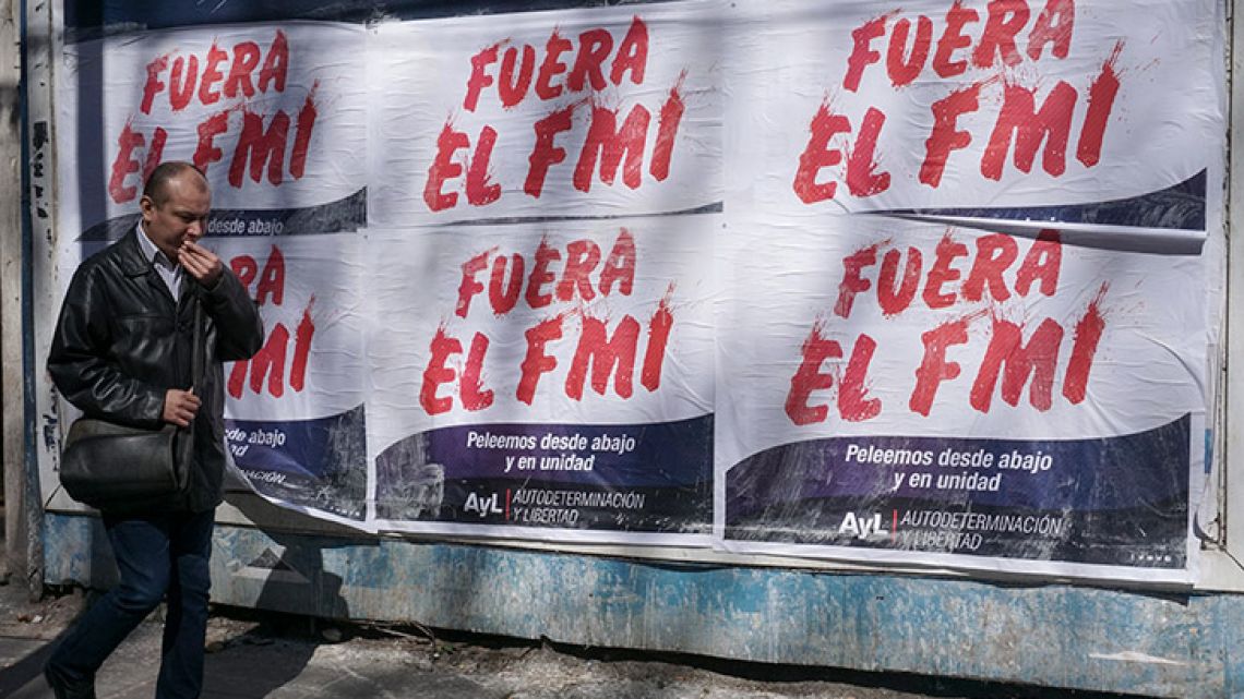 A man walks past posters rejecting the government's negotiations with the International Monetary Fund in Buenos Aires.