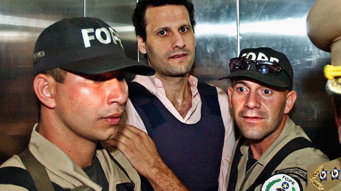 In this November 2003 file photo, Lebanese citizen Assad Ahmad Barakat, who was then facing tax evasion charges, is escorted by police to a courthouse in Asunción, Paraguay.