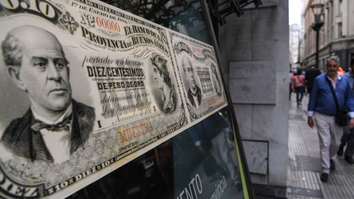 People walk past a bank's branch decorated with images of old peso bills in Buenos Aires.