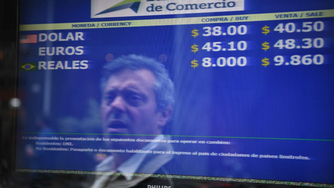 A passerby is reflected in the buy-sell board of a bureau de exchange in Buenos Aires.