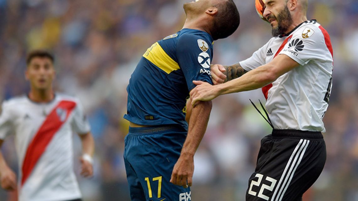 Ramón Ábila of Boca Juniors, centre, challenges for the ball with Javier Pinola of River Plate during the first leg of the Copa Libertadores final at the Bombonera.