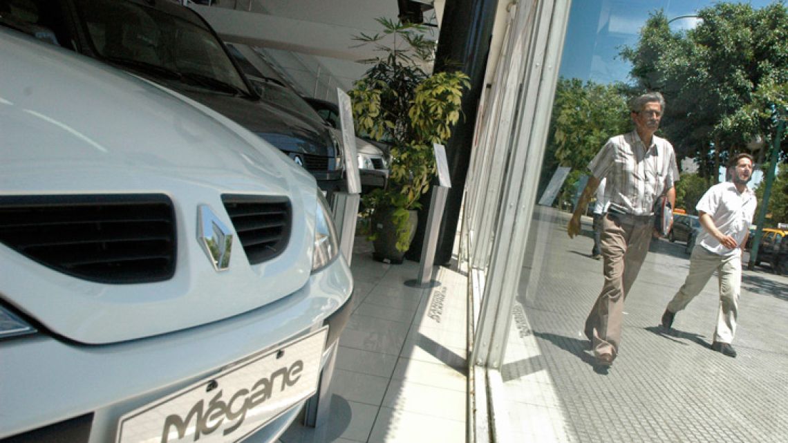 Porteños walk past a car salesroom in Buenos Aires.