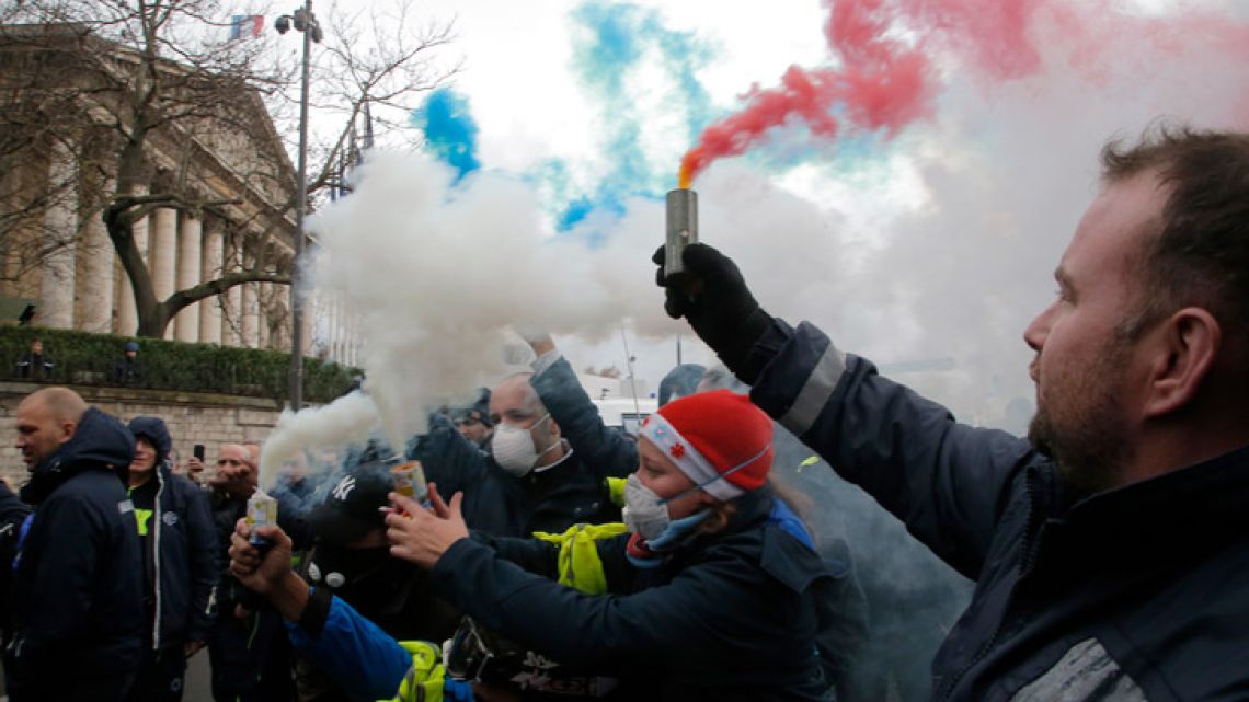 Ambulance workers hold flares outside the National Assembly in Paris, Monday, Dec. 3, 2018. 