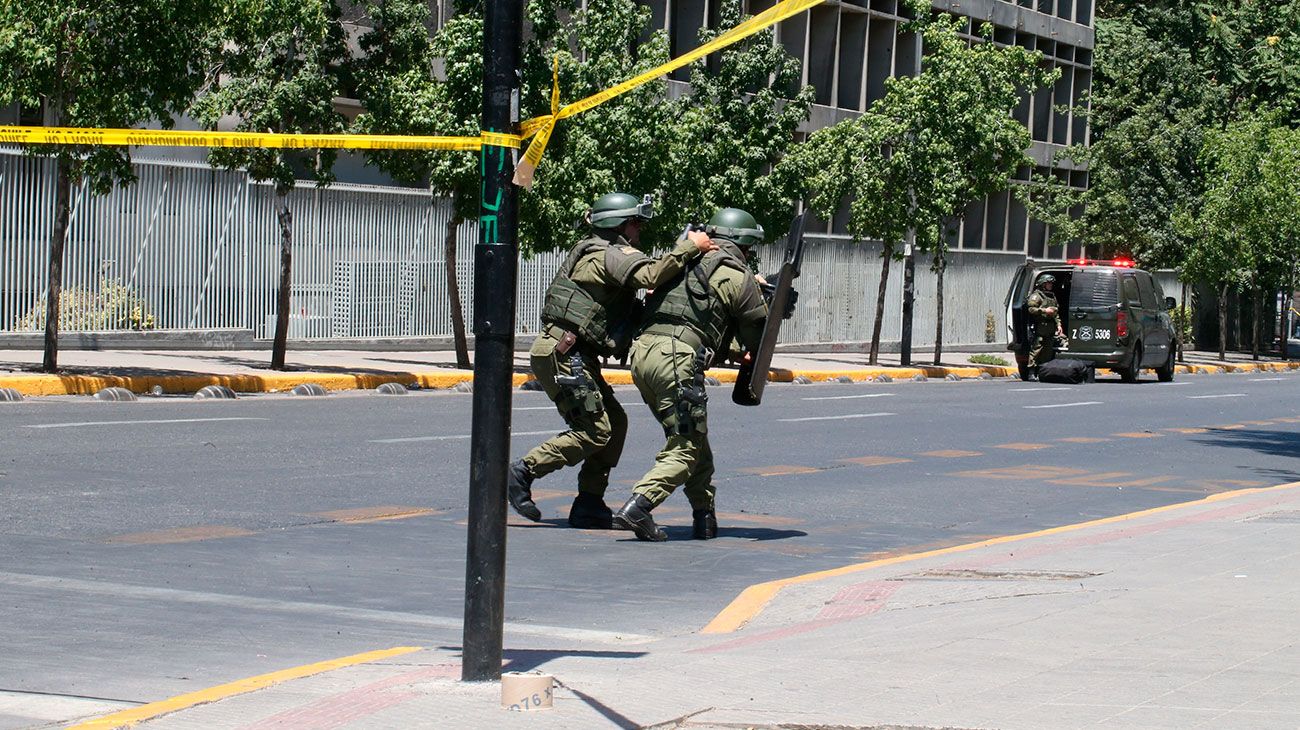 Miembros del Grupo de Operaciones Especiales de la Policía Chilena buscan cerca de una parada de autobús donde varias personas resultaron heridas luego de la explosión, en Santiago, Chile.
