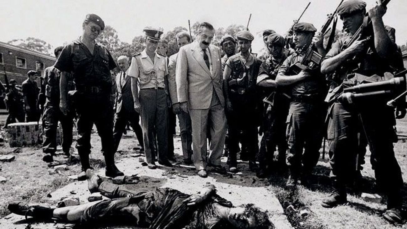 El entonces presidente Raúl Alfonsín observa el cadáver de una militante muerta tras el copamiento.