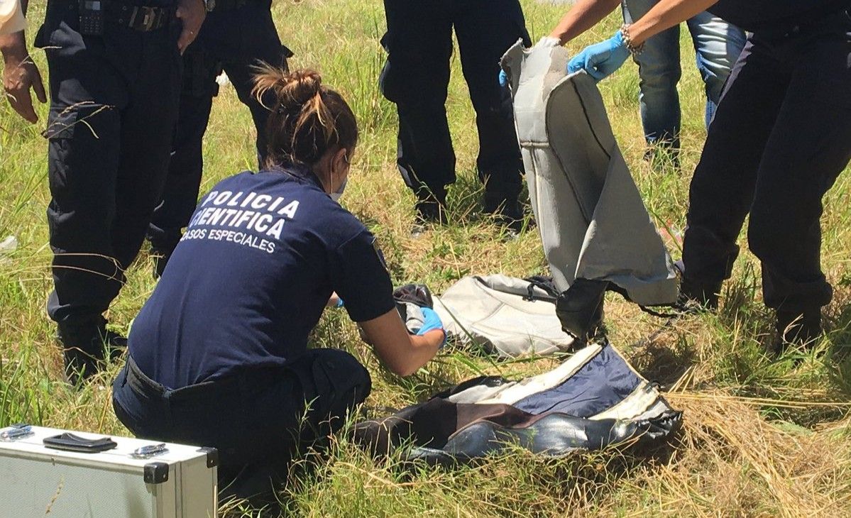 Peritos de la Policía Científica de Buenos Aires trabajan en los objetos hallados a la vera de la ruta 6