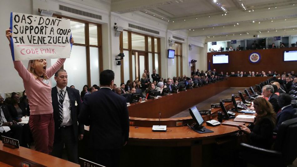 Una manifestante mostró en la sesión de la OEA un cartel sobre "el golpe en Venezuela".