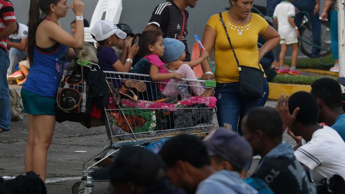 Central American women with their children resting in a supermarket cart wait to enter a Mexican migration office to register for a humanitarian visa in January 2019.