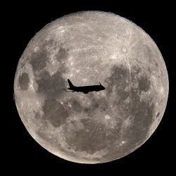 An Embraer 190-100IGW plane (registration LV-CKZ) of Aerolineas Argentinas, on a regular flight from Buenos Aires to Bahía Blanca, passes in front of the "Supermoon" as seen from Buenos Aires on February 19, 2019. 