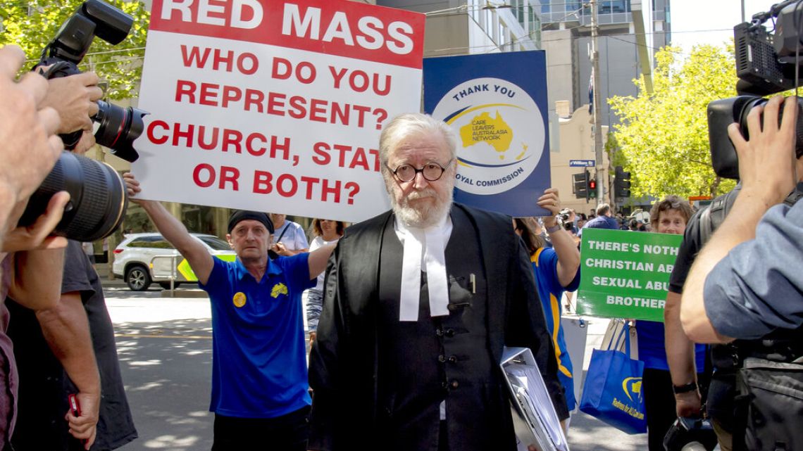 Cardinal George Pell's lawyer Robert Richter leaves the County Court as protesters hold placards in Melbourne, Australia, Wednesday, Feb. 27, 2019
