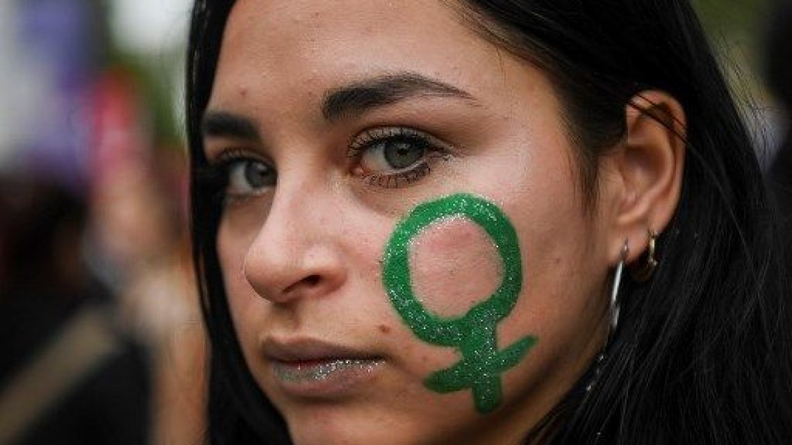 Women sport green bandanas and body paint to support abortion rights in Argentina. 