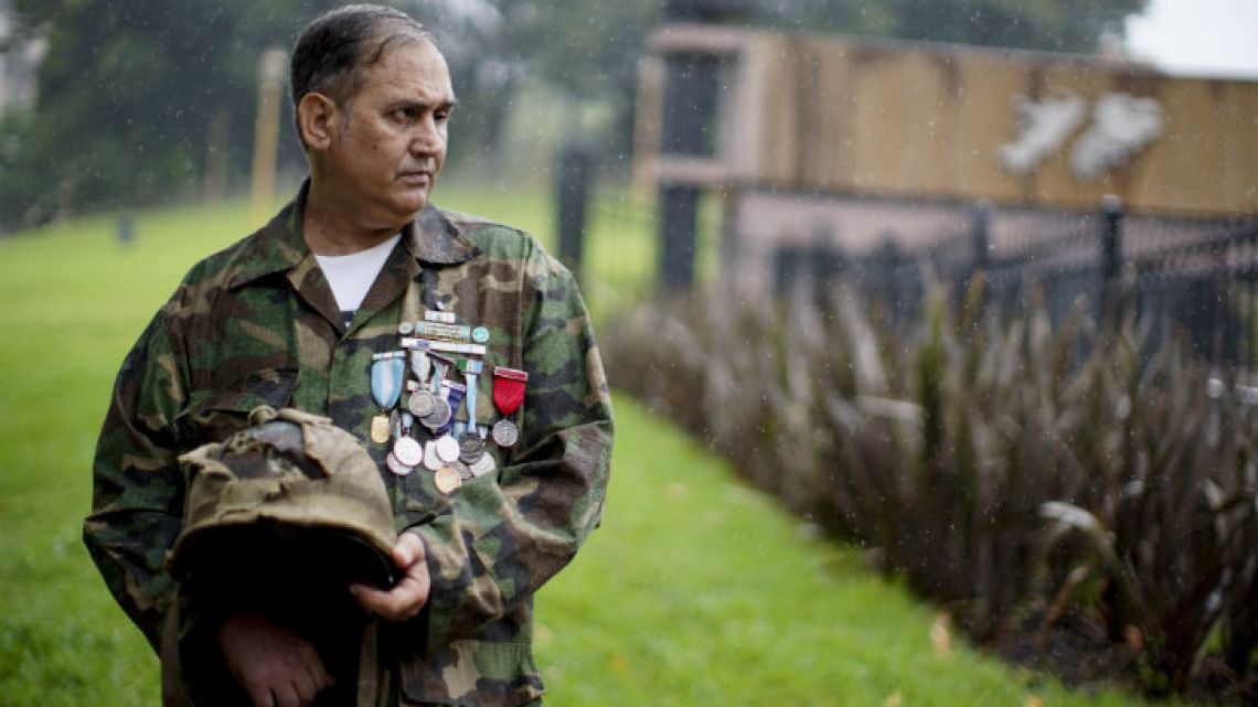 War veteran Jorge Altieri poses for a portrait with the blood-stained helmet that saved his life in 1982.