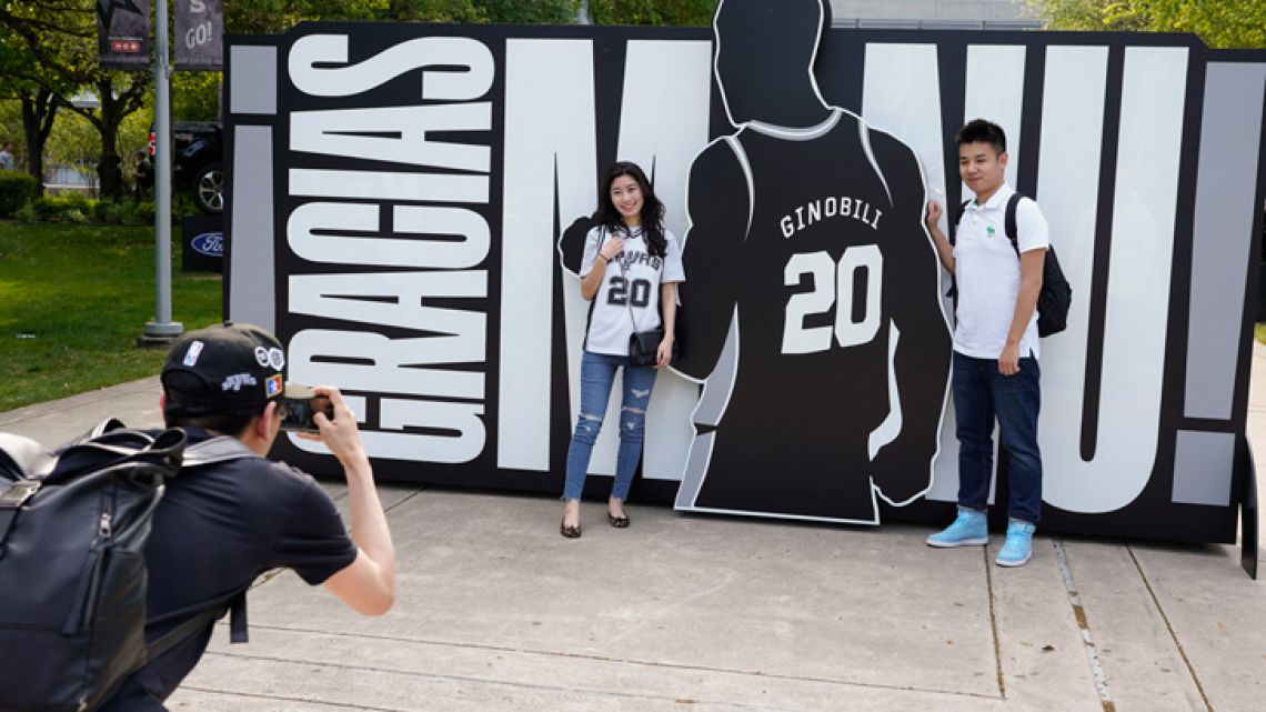 San Antonio Spurs fans pose for a photo in front of a sign thanking Manu Ginóbili before an NBA basketball game against the Cleveland Cavaliers on Thursday.