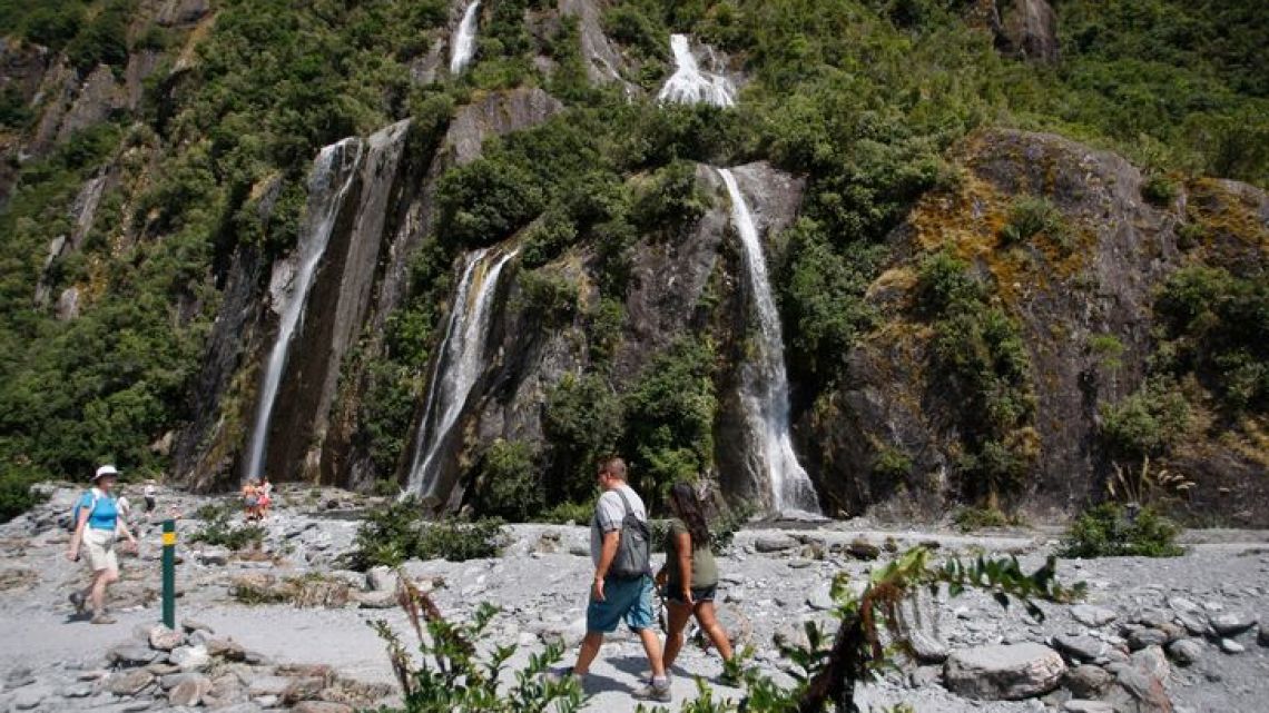 Tourists walk by waterfalls at the Franz Josef Glacier in New Zealand in February of 2016. The Fox and Franz Josef glaciers have been melting so rapidly in recent years that it has become to dangerous for tourists to hike onto them from the valley floor. 