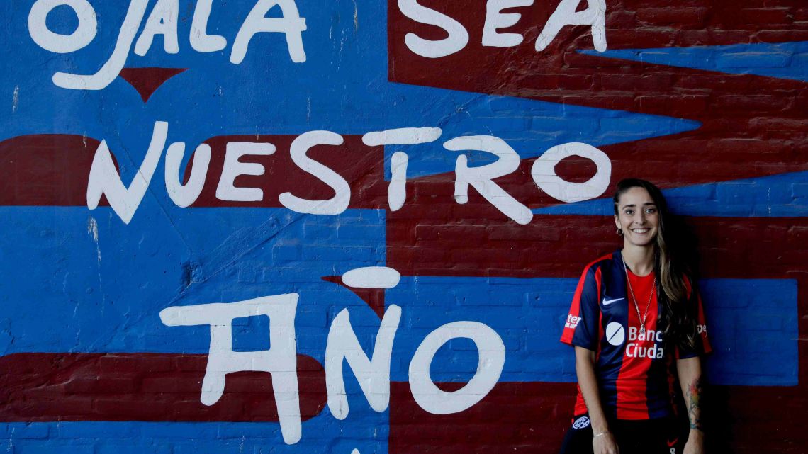Macarena Sanchez poses for a photo against a mural with a message that reads in Spanish: "Hope this will be our year," after signing professional contracts at the San Lorenzo soccer club, in Buenos Aires, Argentina, Friday, April 12, 2019.