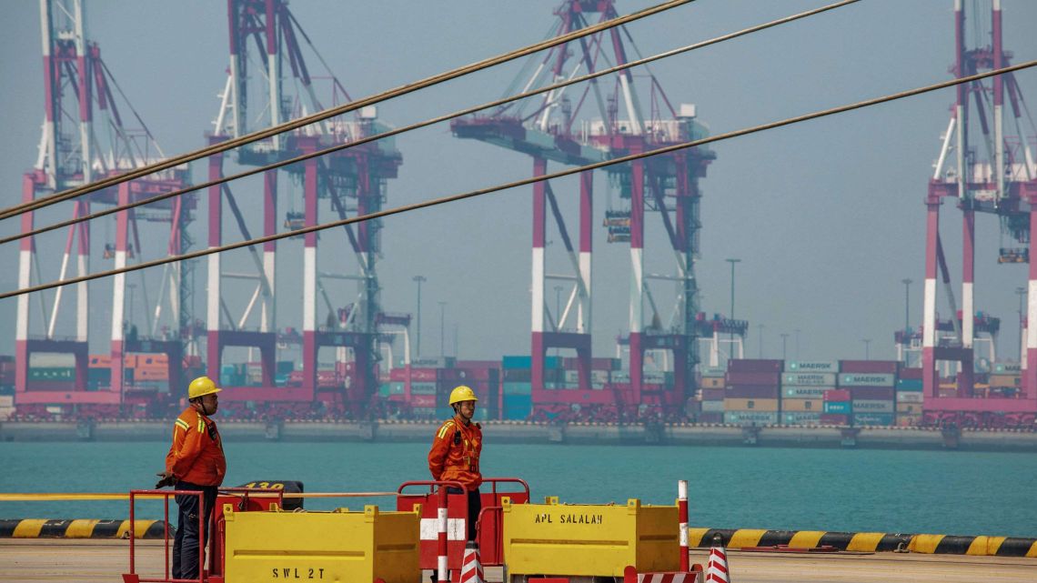 Two staff members stand at a port in Qingdao in China's eastern Shandong province on April 17, 2019. China's economy beat forecasts as it remained steady with 6.4 percent growth in the first quarter amid tepid global demand, a US trade war and a debt battle, official data showed on April 17.