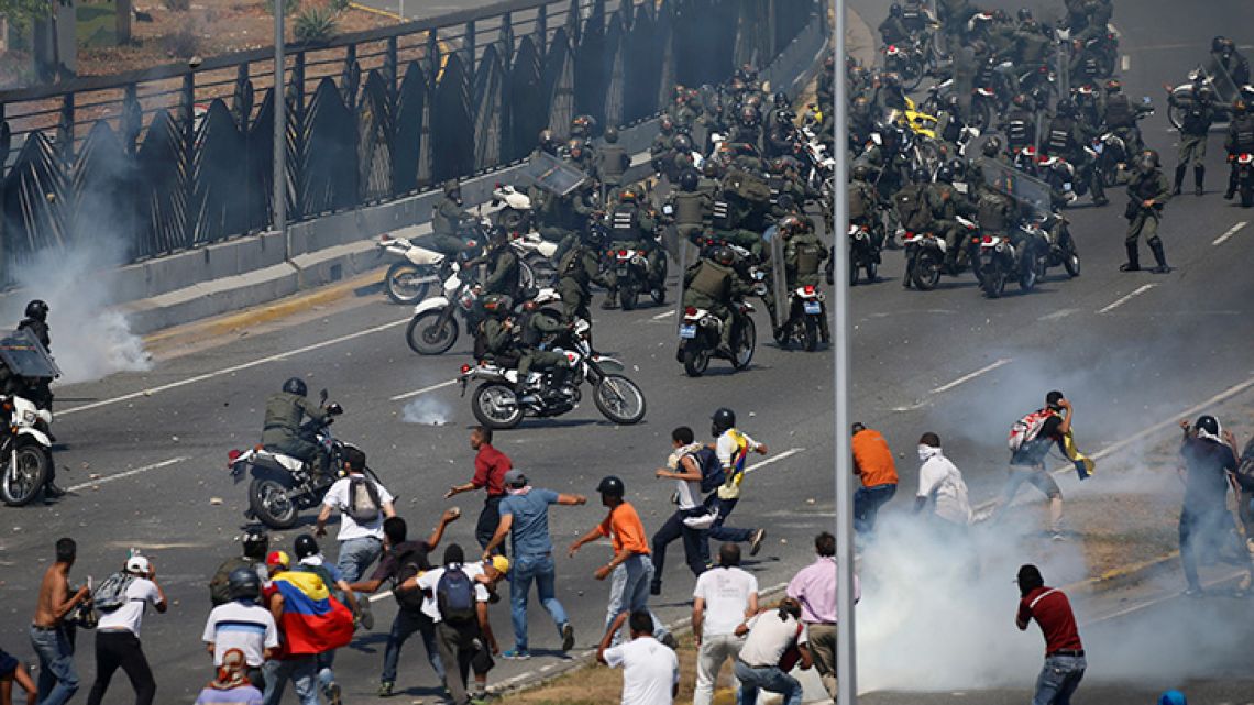 Opponents to Venezuela's President Nicolás Maduro confront loyalist Bolivarian National Guard troops firing tear gas at them, outside the La Carlota military airbase in Caracas.