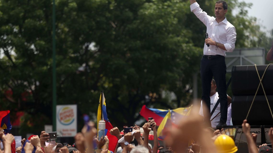 Venezuelan opposition leader Juan Guaidó gestures at supporters during a rally to commemorate May Day on May 1, 2019 after a day of violent clashes on the streets of the capital spurred by his call on the military to rise up against President Nicolas Maduro.