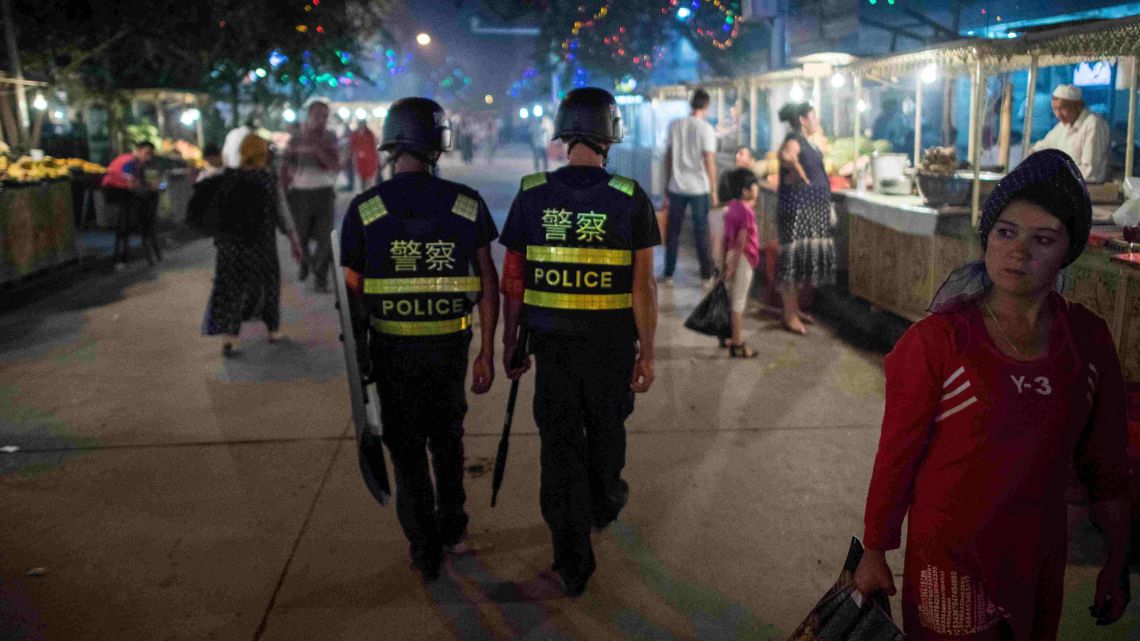 Police patrol a night food market near the Id Kah Mosque in Kashgar in China's Xinjiang Uighur Autonomous Region, a day before the Eid al-Fitr holiday.