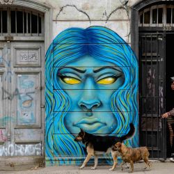 Youngsters and dogs are seen next to a street mural in Valparaiso, Chile, on April 09, 2019.