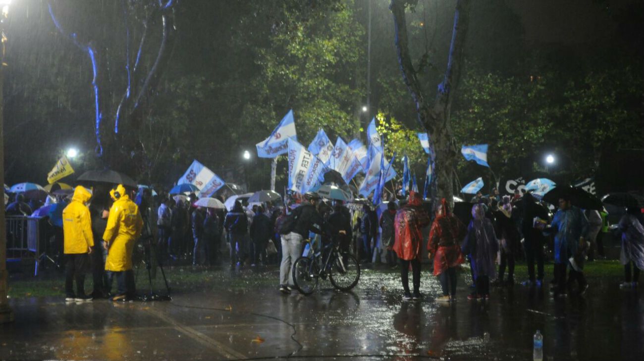 Bajo la lluvia, simpatizantes de la expresidenta esperan por la transmisión en pantalla gigante del evento.