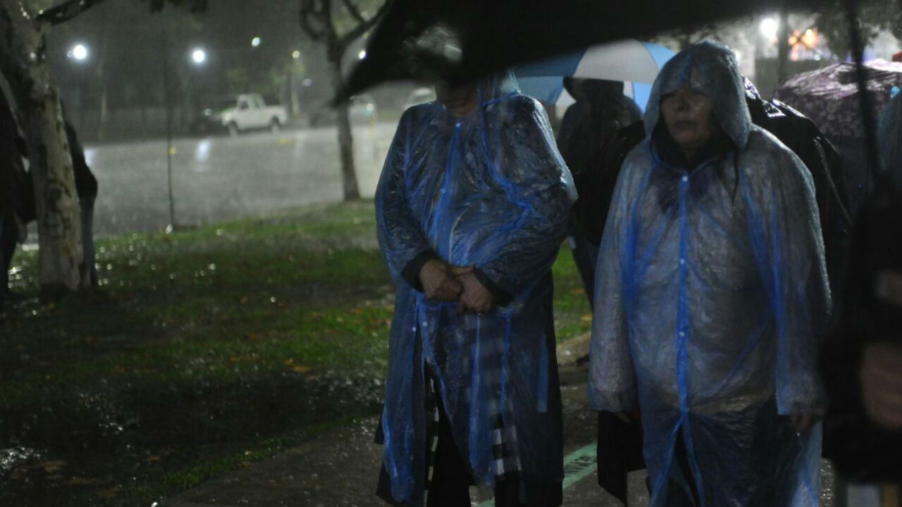 Bajo la lluvia, simpatizantes de la expresidenta esperan por la transmisión en pantalla gigante del evento.