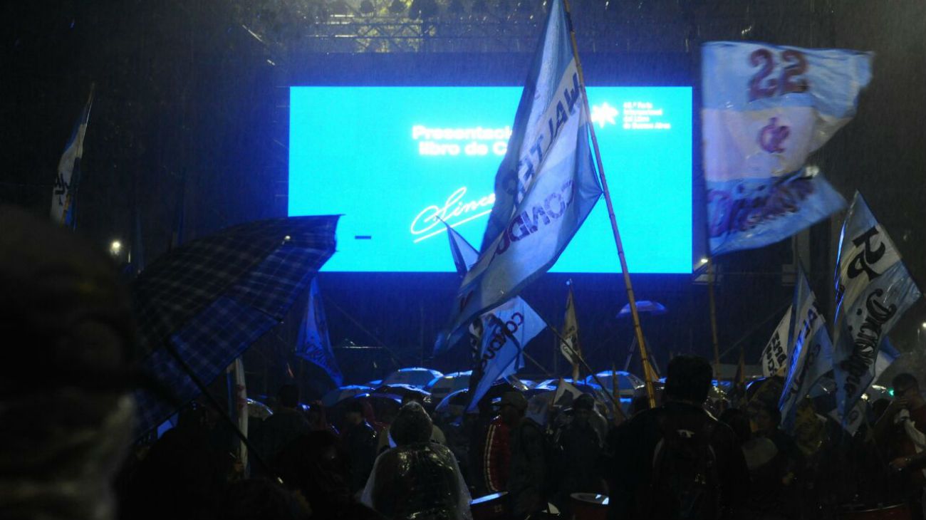 Bajo la lluvia, simpatizantes de la expresidenta esperan por la transmisión en pantalla gigante del evento.