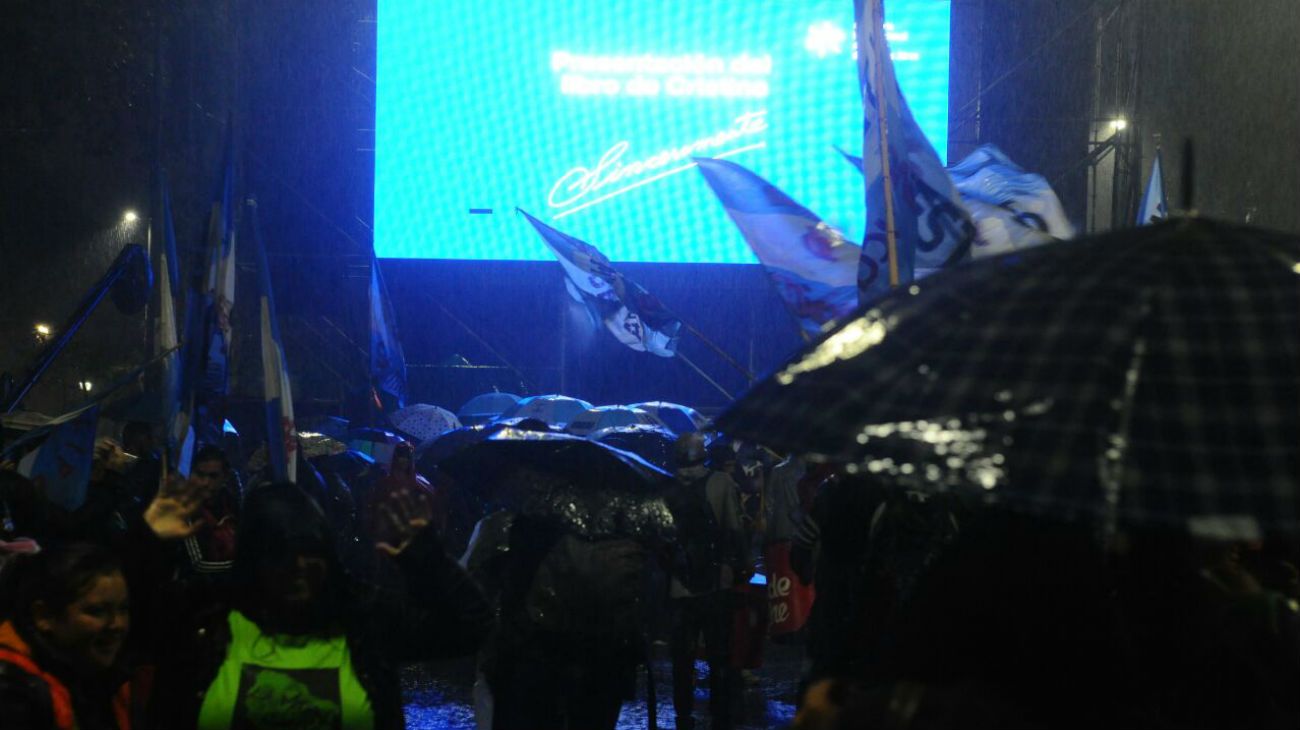 Bajo la lluvia, simpatizantes de la expresidenta esperan por la transmisión en pantalla gigante del evento.