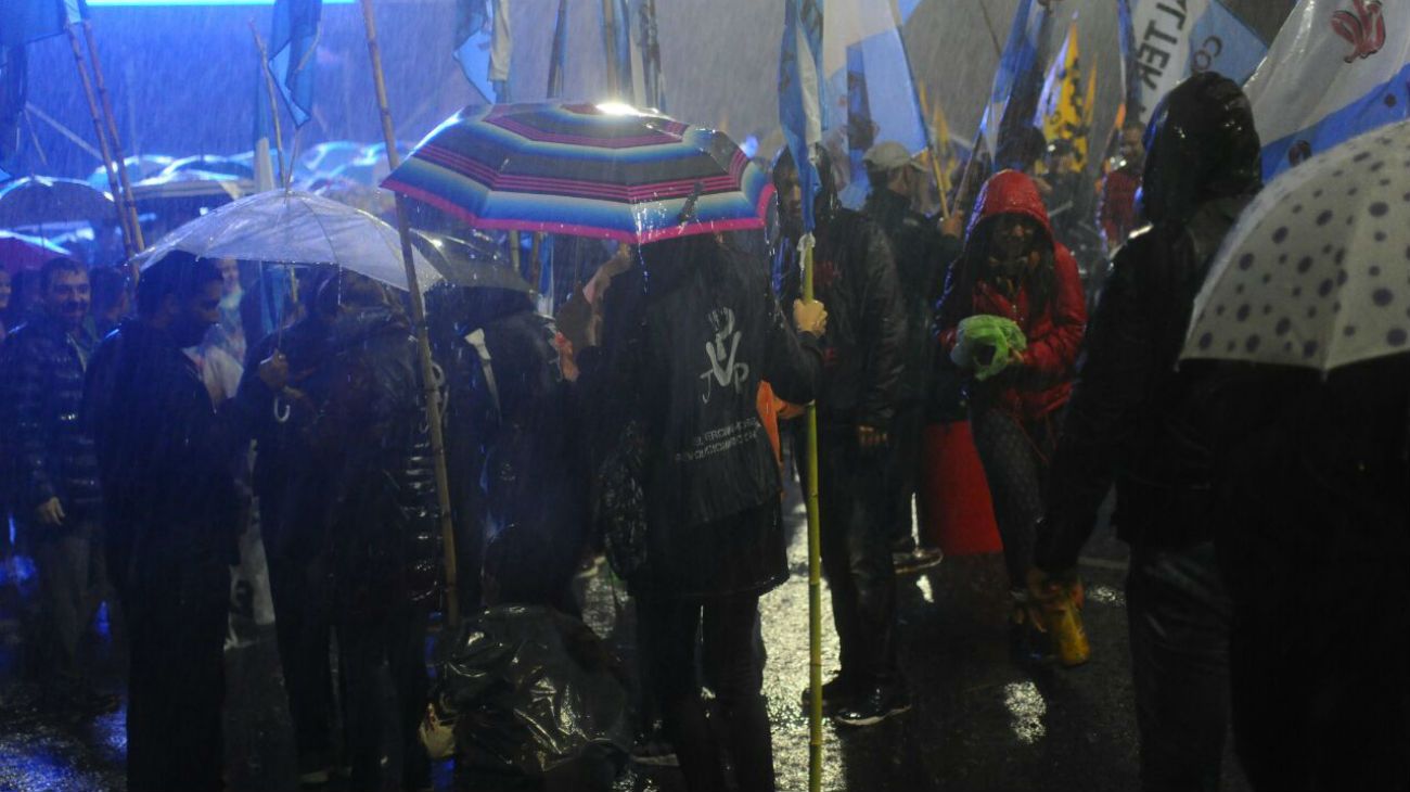 Bajo la lluvia, simpatizantes de la expresidenta esperan por la transmisión en pantalla gigante del evento.