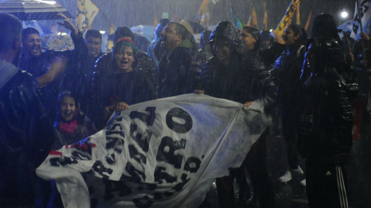 Bajo la lluvia, simpatizantes de la expresidenta esperan por la transmisión en pantalla gigante del evento.