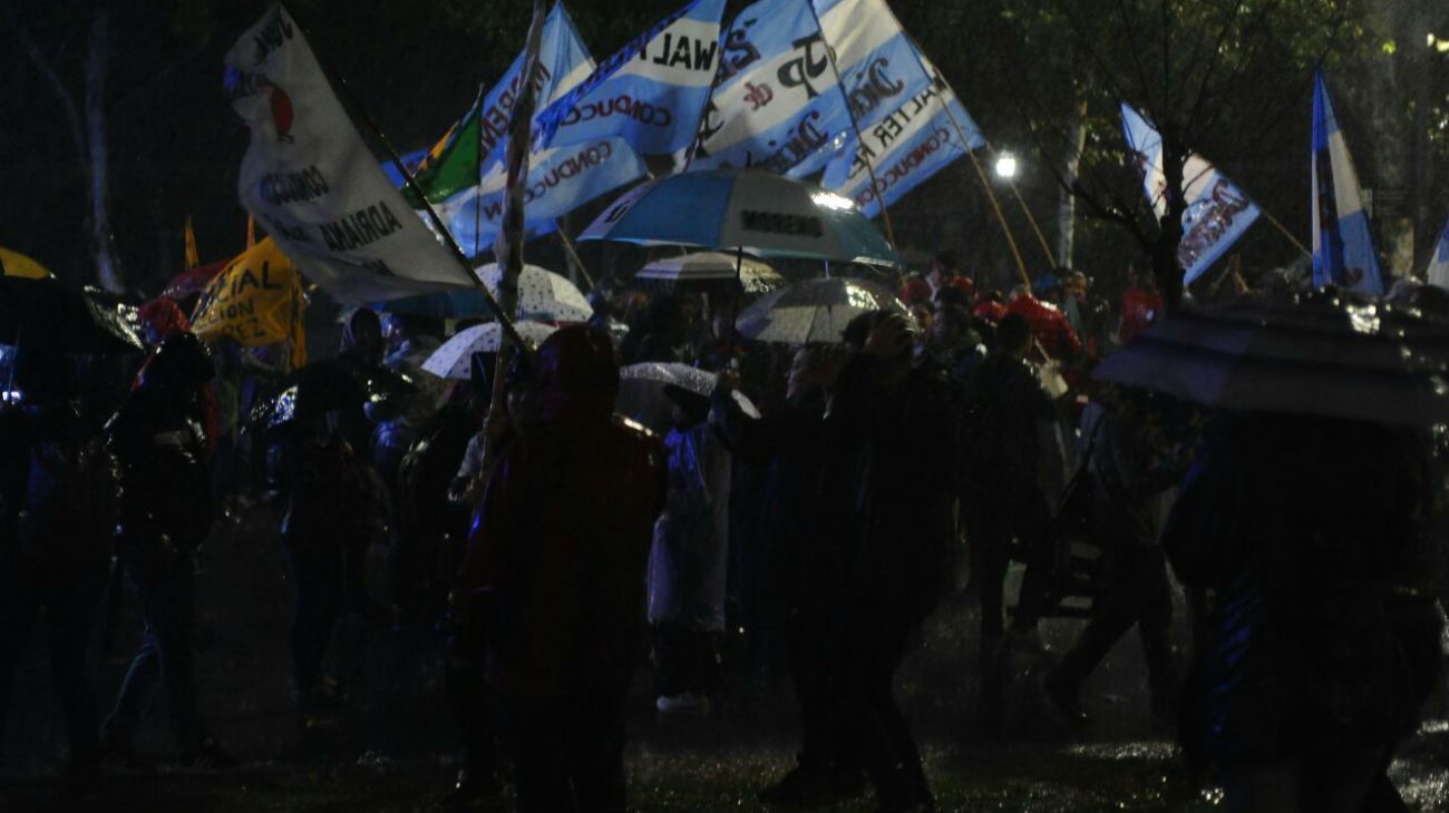 Bajo la lluvia, simpatizantes de la expresidenta esperan por la transmisión en pantalla gigante del evento.