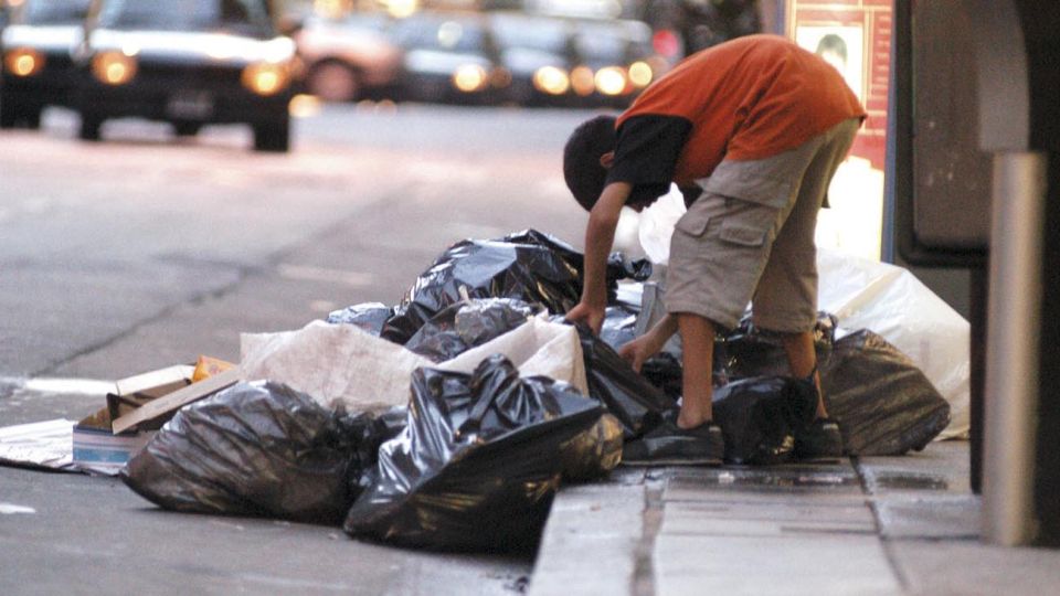 Un chico revolviendo la basura. Postal de la pobreza.
