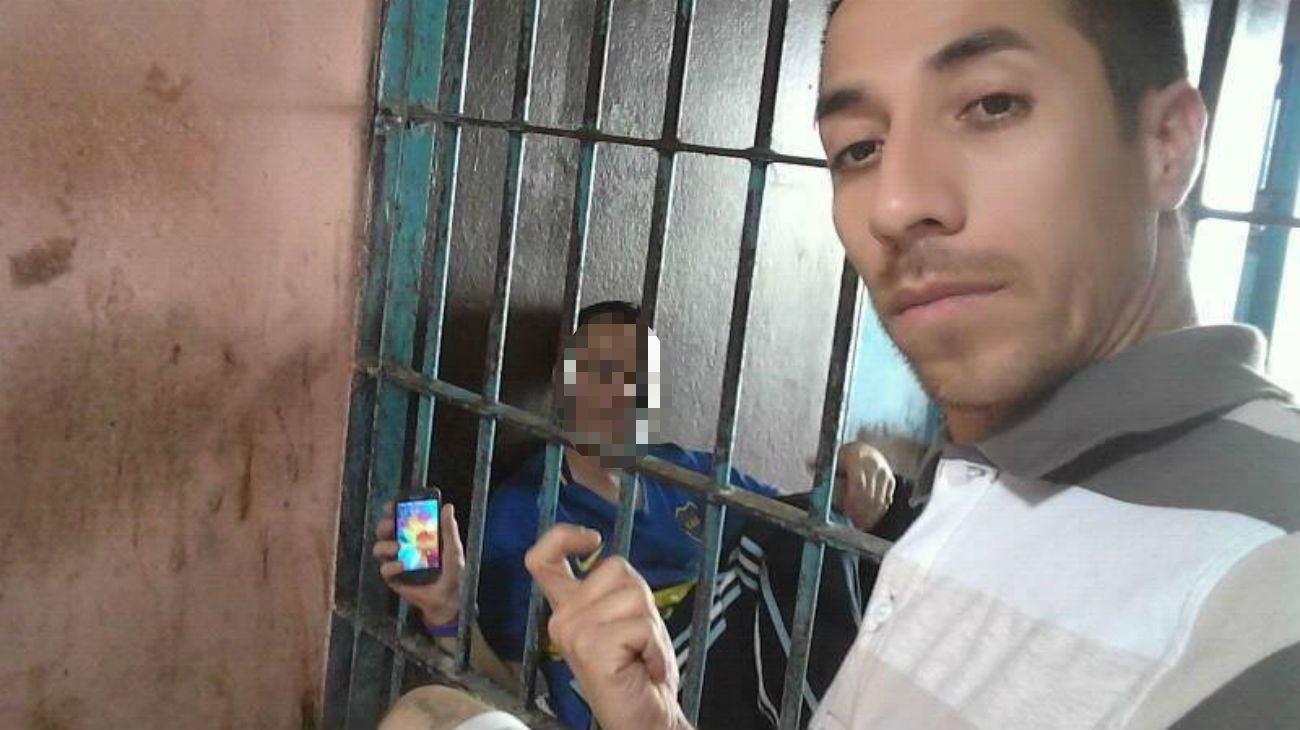 En el calabozo, con un preso amigo que también muestra su teléfono celular.