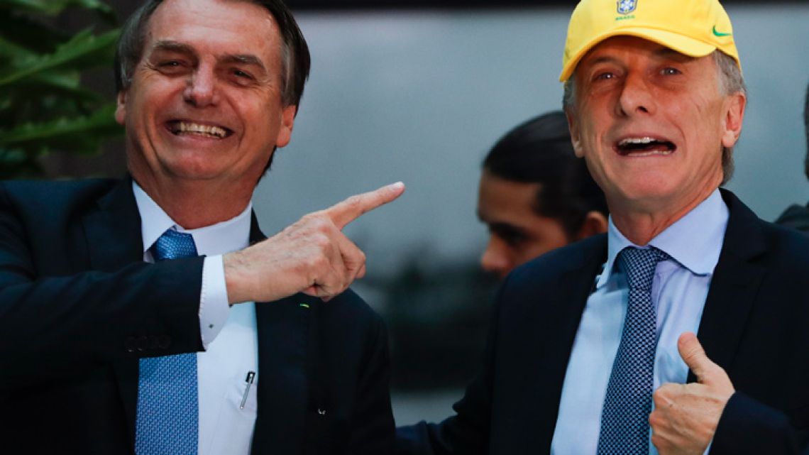 Brazil's President Jair Bolsonaro gives a hat to Argentina's President Mauricio Macri before the two took lunch in Buenos Aires this afternoon.