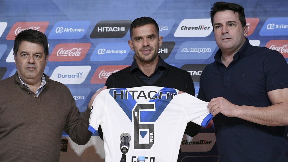 Fernando Gago (centre) holds up a Vélez shirt at his presentation ceremony.