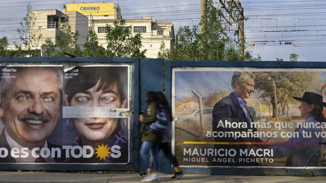 People walk past political advertising for Juntos por el Cambio and Frente de Todos, in Buenos Aires.