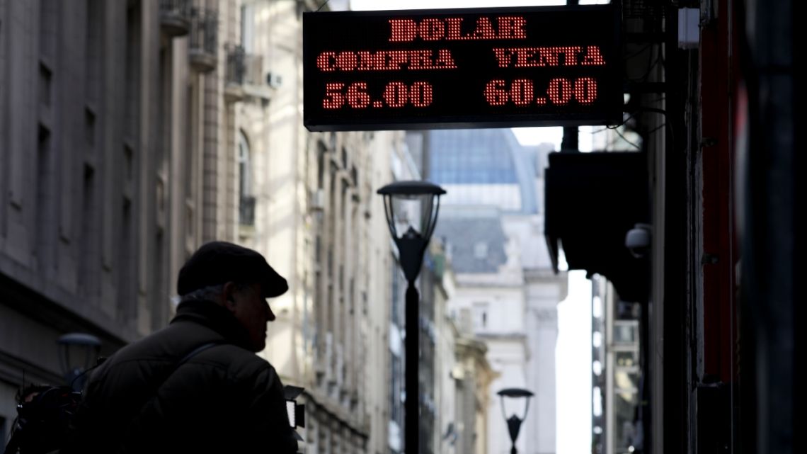 Man looks at rates posted on a currency exchange in Buenos Aires.