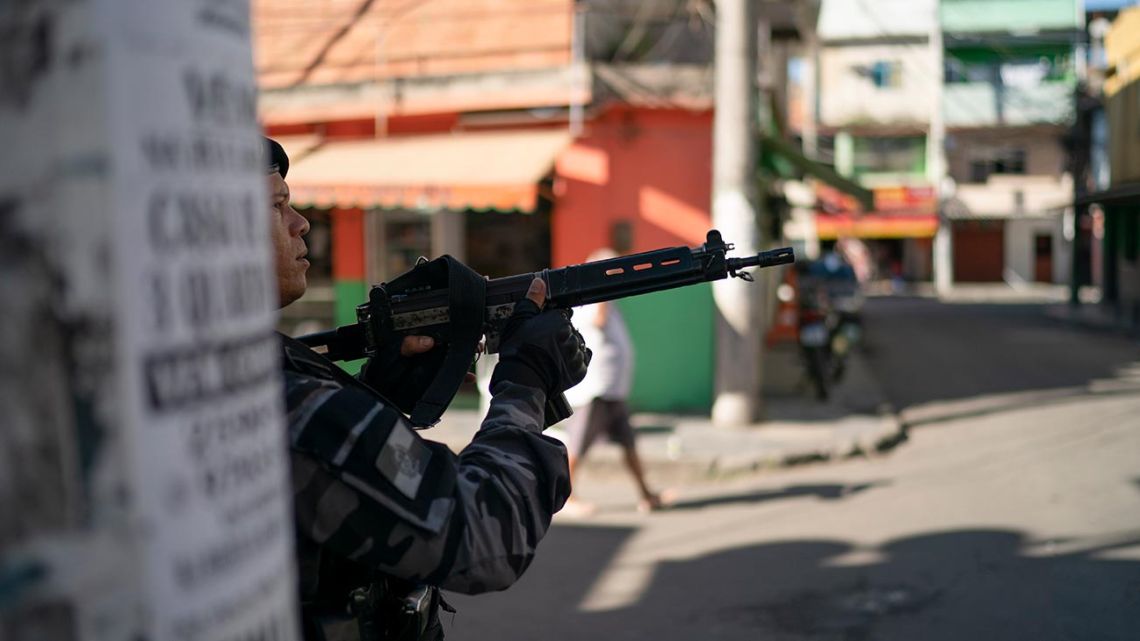 In this July 31, 2019 photo, a police officer aims his weapon during an operation at the Mare complex slum in Rio de Janeiro, Brazil. Many Brazilians see police-caused deaths as a regrettable but acceptable price for cracking down on the country's rampant crime problem. 