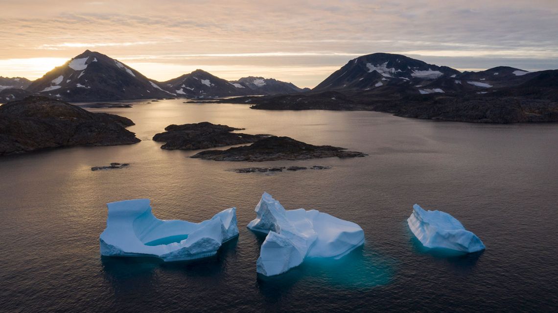 In this Aug. 16, 2019, photo, large Icebergs float away as the sun rises near Kulusuk, Greenland. Scientists are hard at work, trying to understand the alarmingly rapid melting of the ice.