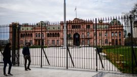 People walk in front the Casa Rosada.