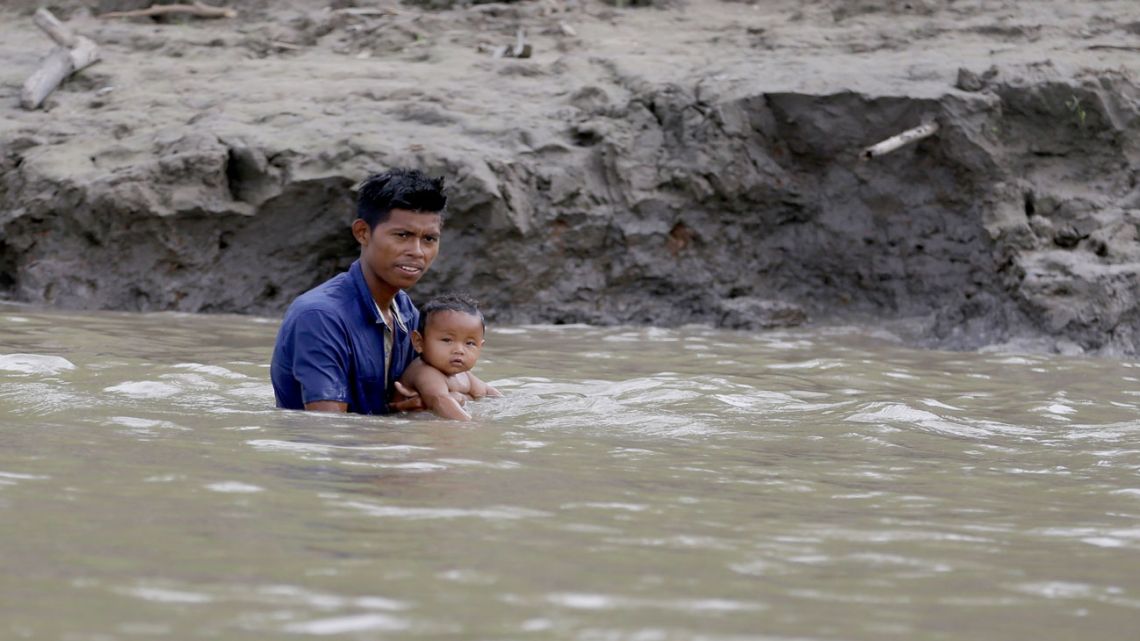 A man holds a baby as they bathe in the Amazon River in Leticia, Colombia, a town where the borders of Colombia, Peru and Brazil meet, Sunday, Sept. 8, 2019.