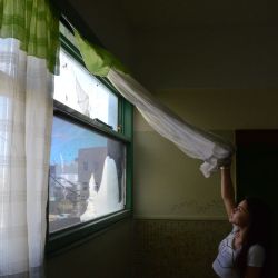 Flor Toledo, 17, looks through a damaged window at Escuela 712 in Trelew. 