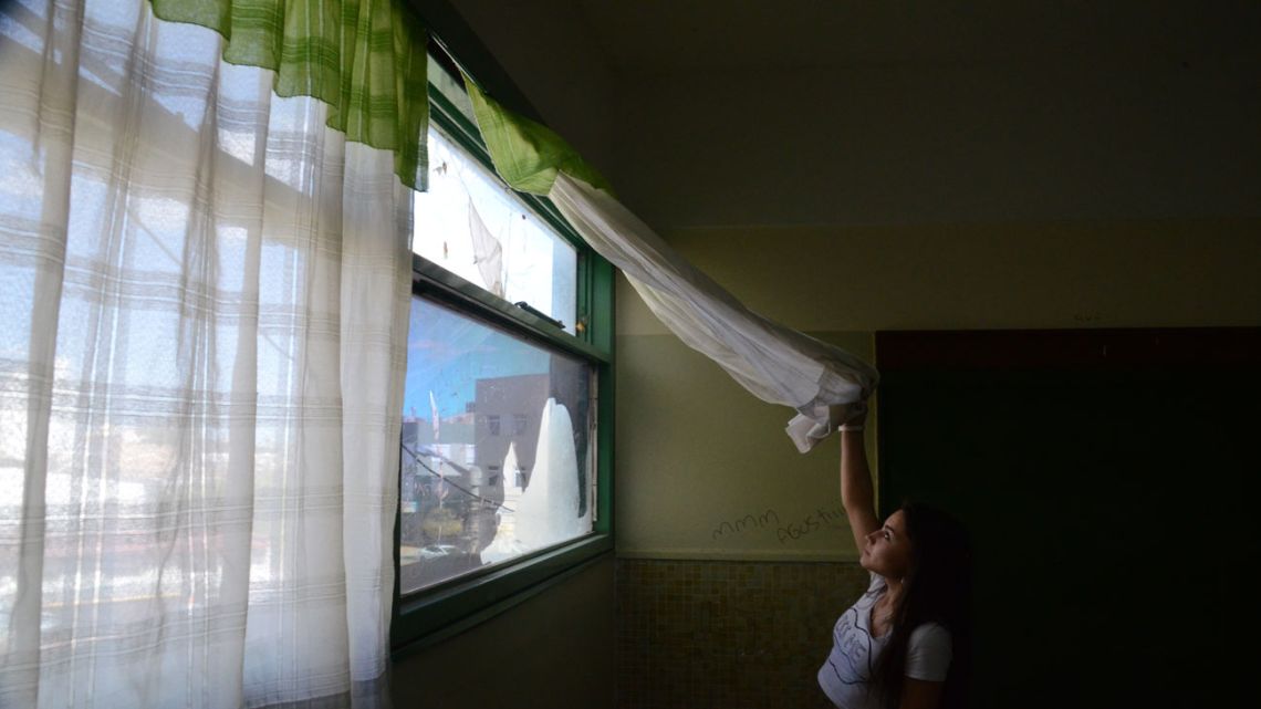 Flor Toledo, 17, looks through a damaged window at Escuela 712 in Trelew. 