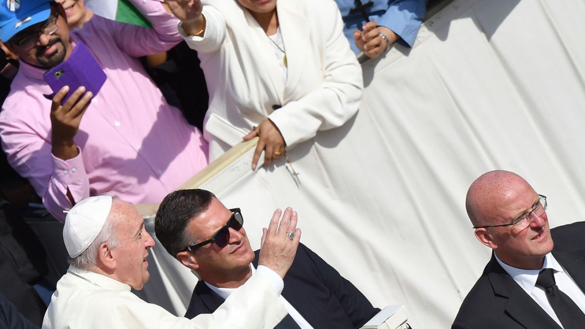 Vatican Gendarmerie chief commander Domenico Giani (right) and Gendarmerie official Luca Cintia (second left) are seen as Pope Francis waves at faithfuls on October 13, 2019 at Saint Peter's square in the Vatican. 