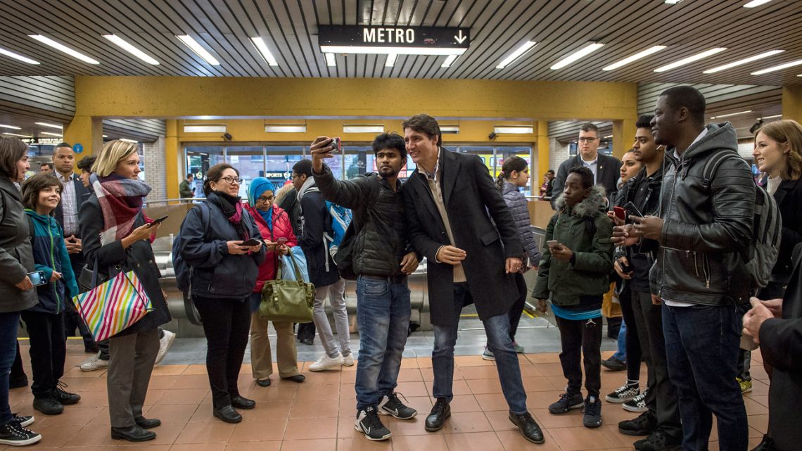 Canadian Prime Minister Justin Trudeau poses with commuters at a metro station in Montreal, the morning after winning re-election.