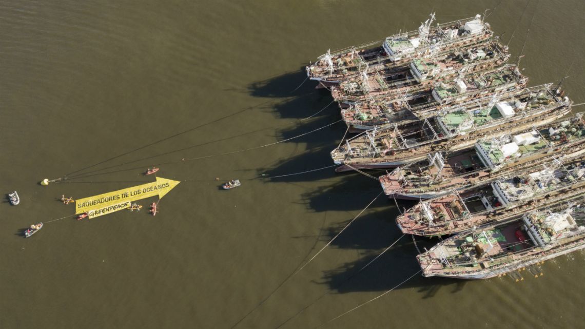 In this aerial handout picture released by Greenpeace, activists of the non-governmental environmental organization display a 25-meter arrow that reads ‘Looters of the Oceans’ pointing to South Korean fishing vessels anchored at the port of Montevideo 