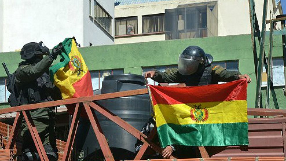 Policías bolivianos del Cuerpo de Operaciones Tácticas cuelgan banderas bolivianas al anunciar que se pliegan al reclamo contra Evo Morales.
